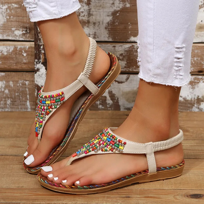 Beige thong sandals with colorful beadwork and elastic ankle strap.