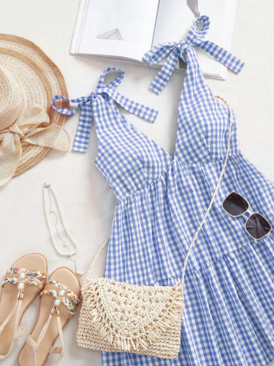 Blue gingham maternity mini dress with tie shoulders and ruffle hem.