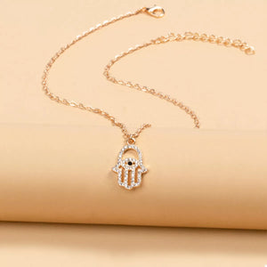 Gold evil eye Hamsa hand necklace with clear rhinestones and a black eye detail.