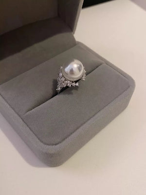 Luminous pearl and silver ring with sparkling accents in a gray jewelry box.