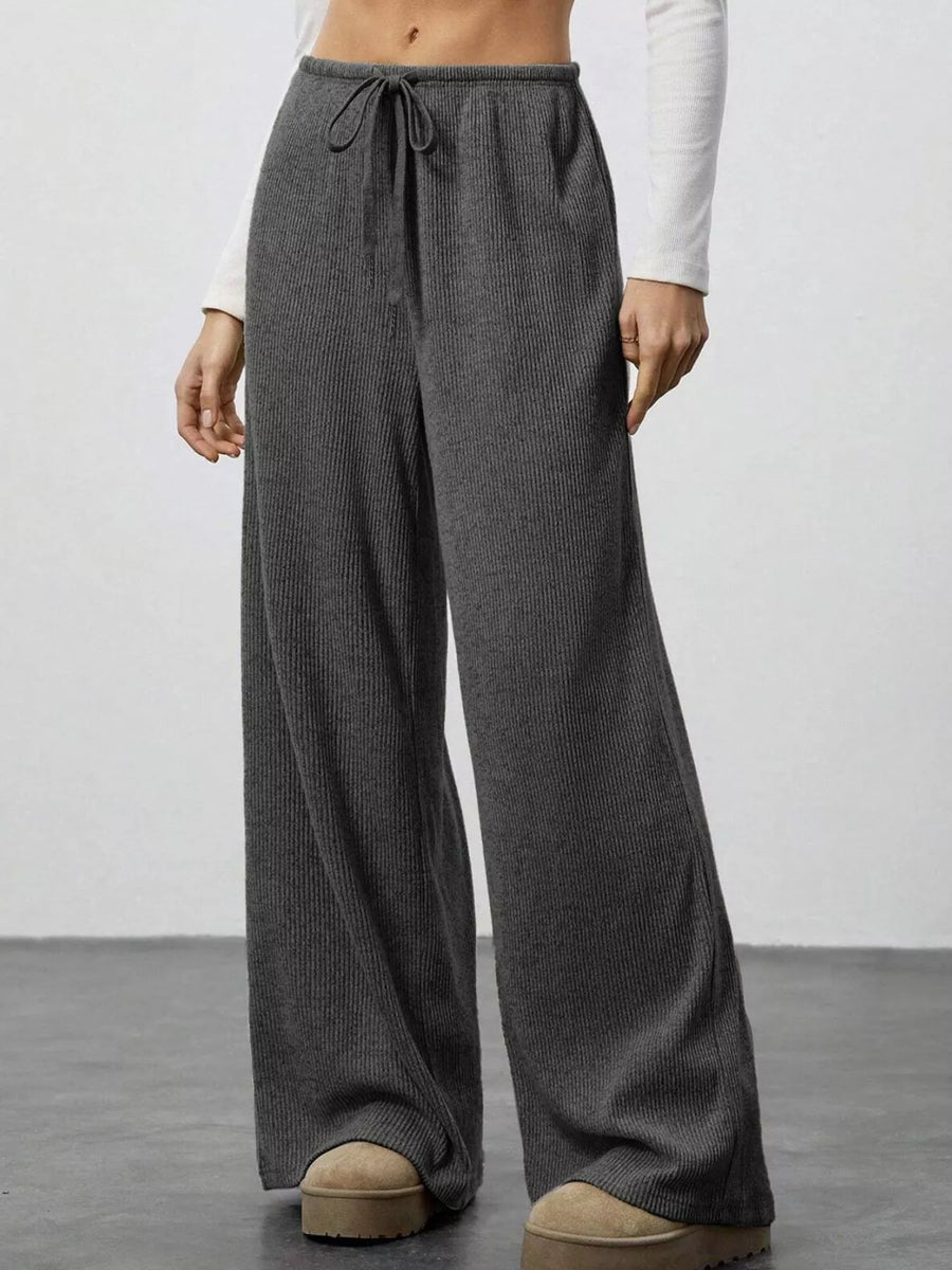 Dark gray ribbed wide-leg pants with drawstring waist and a relaxed fit.