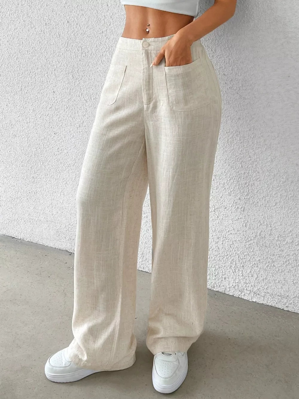 Cream wide-leg linen pants with button closure and dual front pockets.