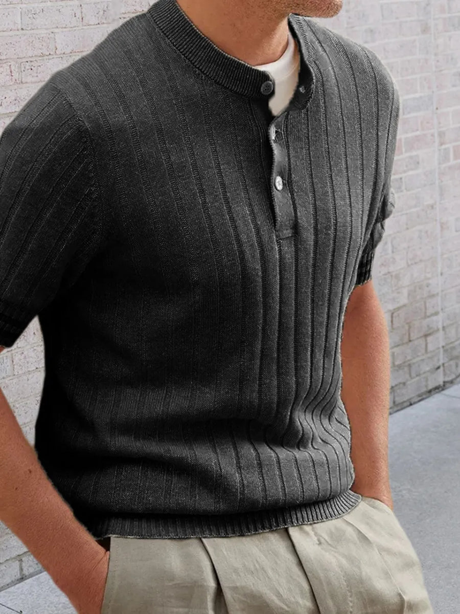 Textured ribbed knit polo shirt in black with short sleeves and a buttoned neckline.
