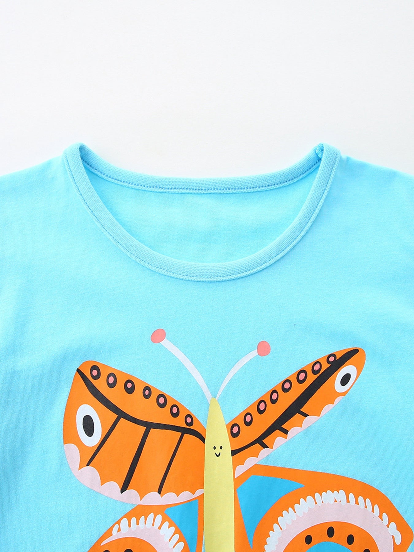 Light blue cotton t-shirt with a charming orange butterfly graphic and round neckline.