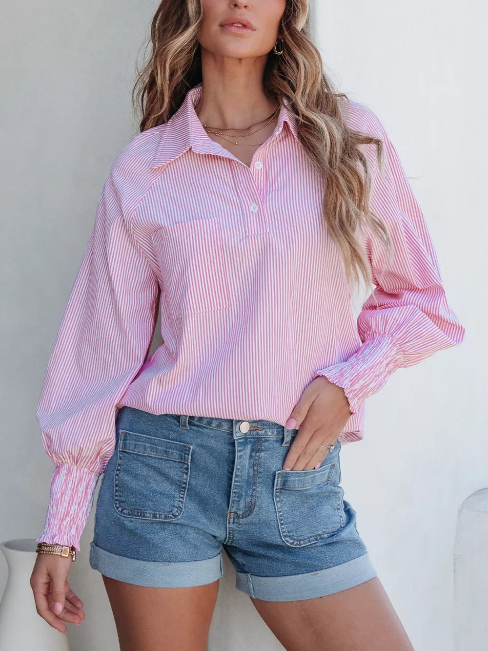 Pink striped button-up shirt with smocked cuffs, paired with cuffed denim shorts.