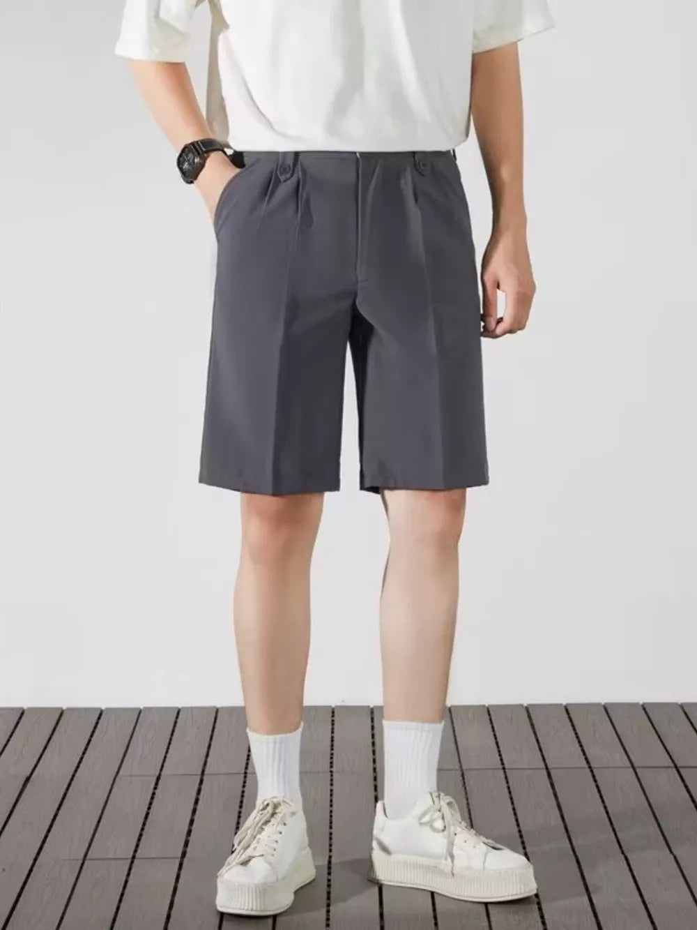 Men's dark gray pleated chino shorts with pockets and a relaxed fit.