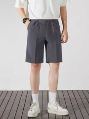 Men's dark gray pleated chino shorts with pockets and a relaxed fit.