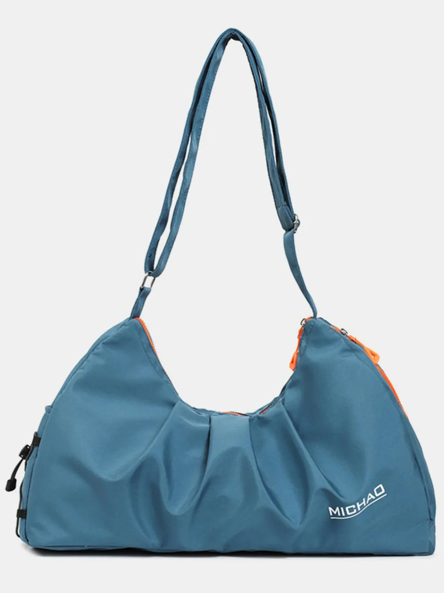 Peacock blue gathered pleat crossbody bag with orange zipper detail and adjustable strap.