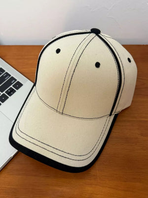 Cream white cotton baseball cap with black contrast stitching and brim detail.