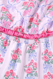 Floral tiered ruffle dress with pink roses and blue bows on a pink striped and polka dot background.