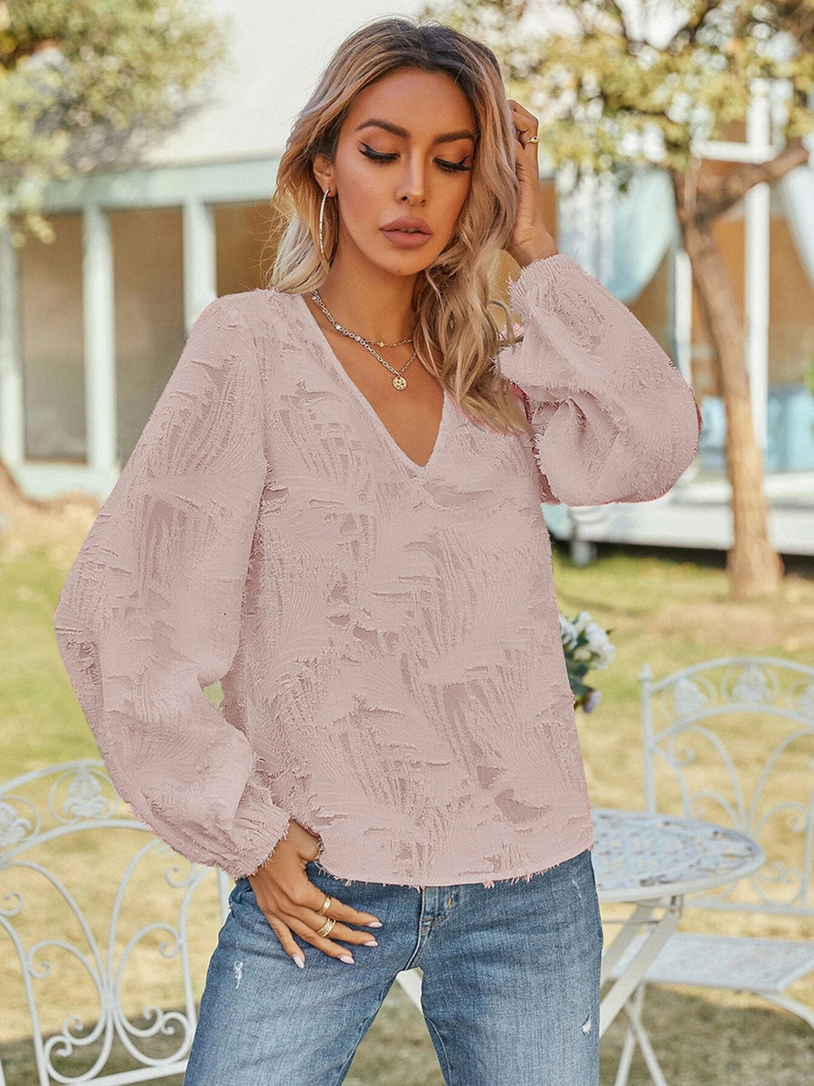 Blush pink textured puff sleeve V-neck blouse with all-over feather-like pattern.