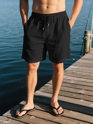 Black linen drawstring shorts with side pockets and a relaxed fit.