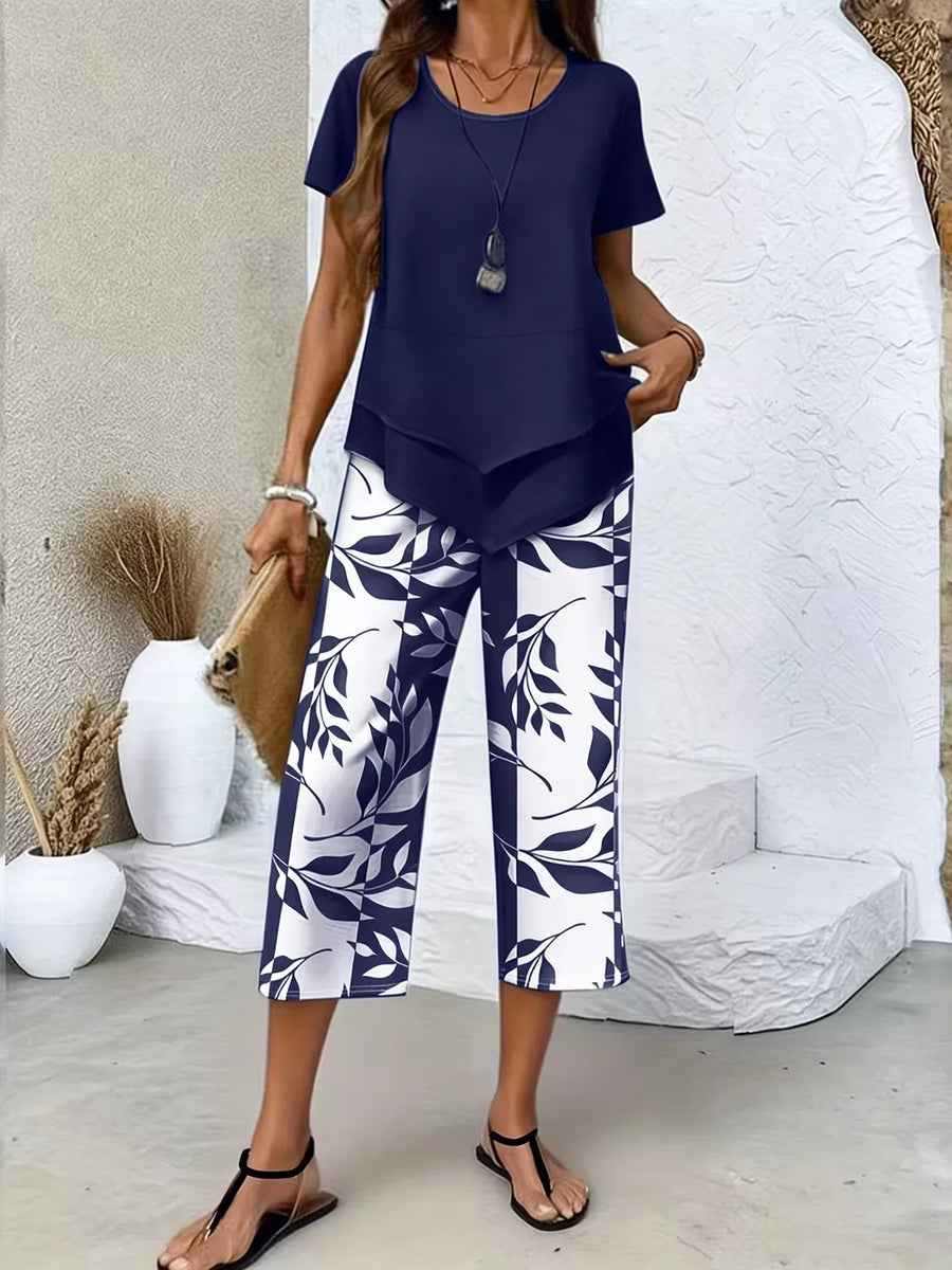 Navy blue layered top with short sleeves and navy and white leaf print cropped pants.