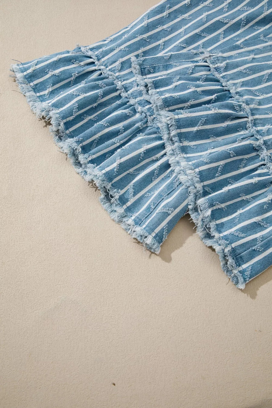 Striped denim overalls with distressed ruffle detail and frayed hem.