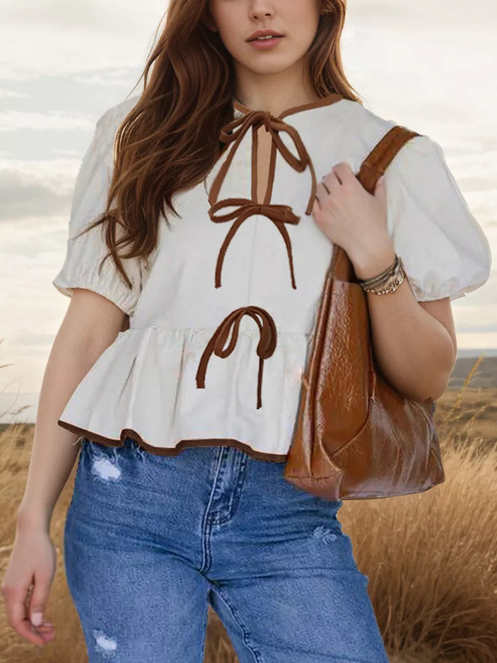 White peplum shirt with puff sleeves, contrast trim, and tie-front detail.