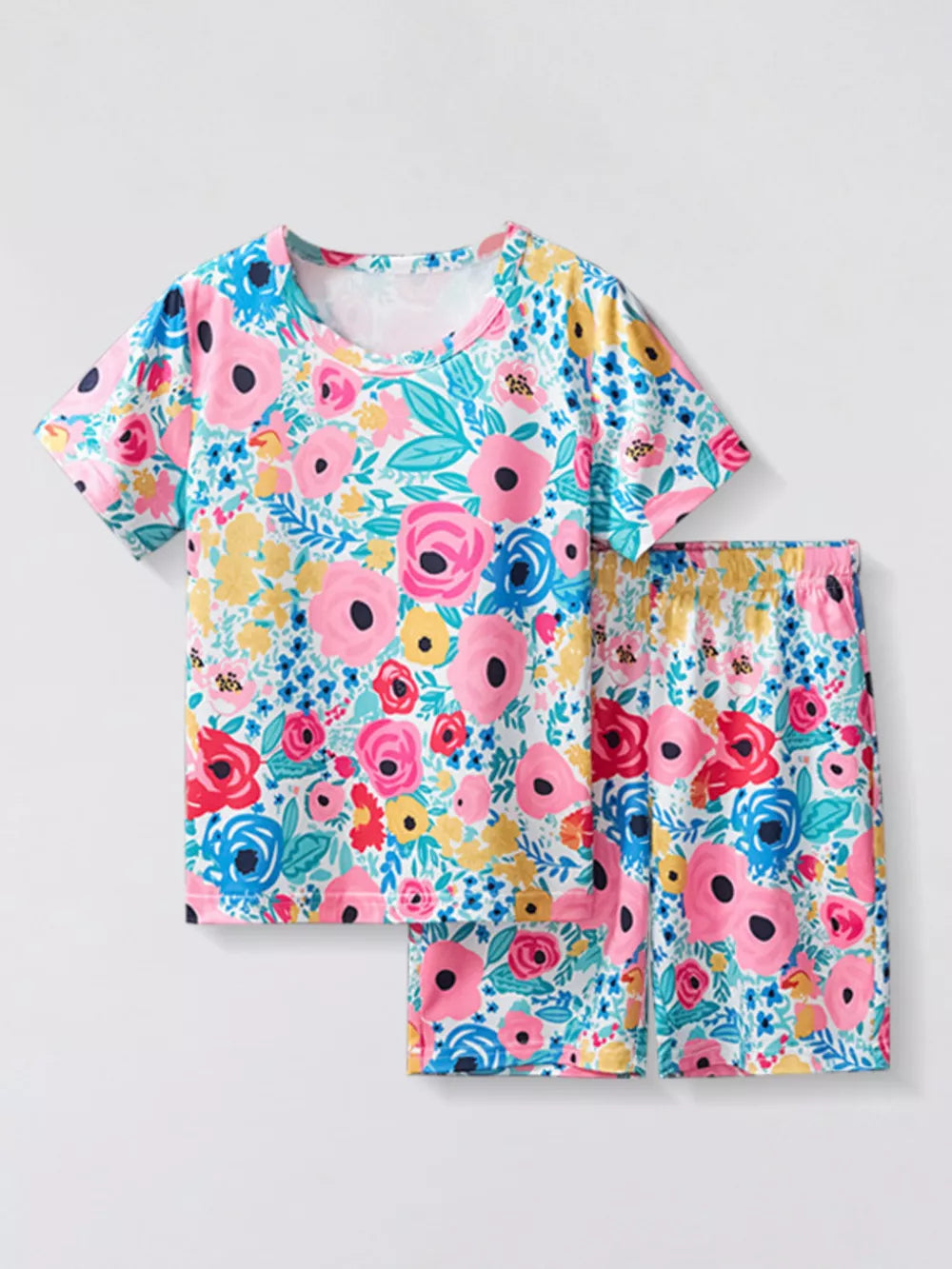 Pajama set with short sleeves and shorts, featuring a vibrant floral print in pink, blue, and yellow on a white background.