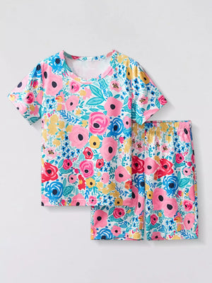 Pajama set with short sleeves and shorts, featuring a vibrant floral print in pink, blue, and yellow on a white background.