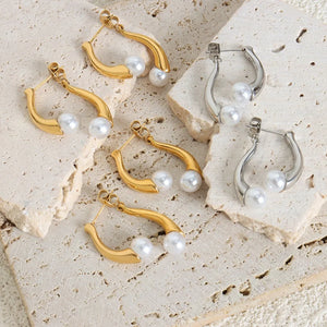 Gold and silver sculptural pearl drop hoop earrings with a modern design.