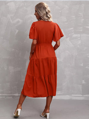 Orange-Red tiered midi dress with flutter sleeves and belted waist.