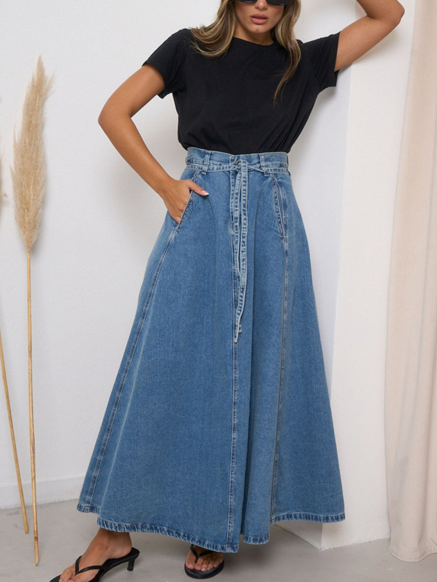 High-waisted A-line denim maxi skirt in light blue with a tie waist and pockets.