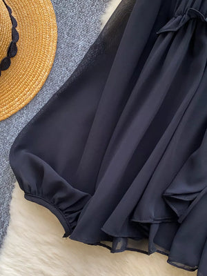 Black chiffon blouse with ruffled tie-front detail and gathered cuffs.