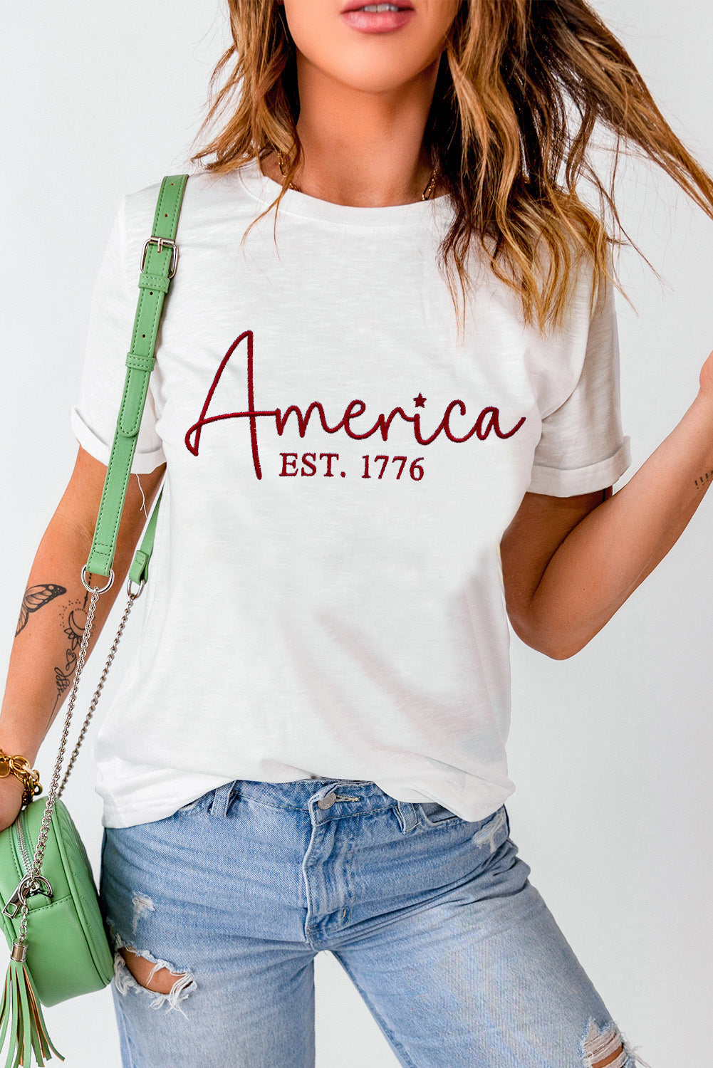 White graphic t-shirt with red "America EST. 1776" text and a star detail.