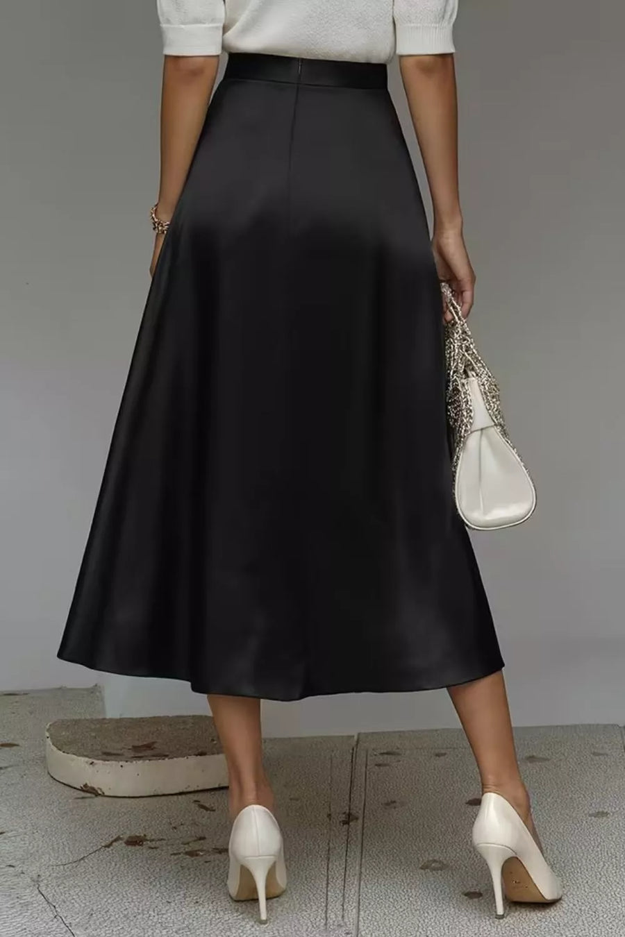 Black a-line midi skirt with a lustrous finish and hidden pockets.