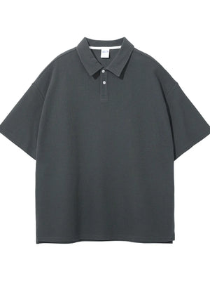 Boxy textured polo shirt in dark gray with a spread collar and two-button placket.