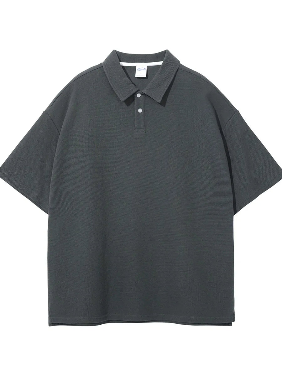 Boxy textured polo shirt in dark gray with a spread collar and two-button placket.