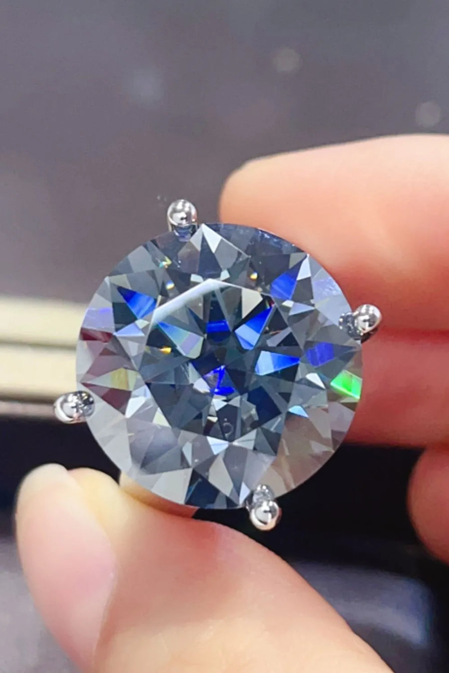 Round moissanite cocktail ring with a large, brilliant-cut center stone and silver prongs.