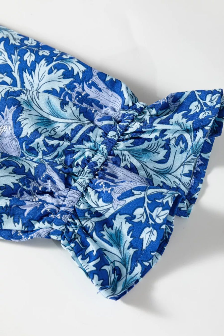 Blue floral cotton midi dress with cinched waist and frilled cuffs.