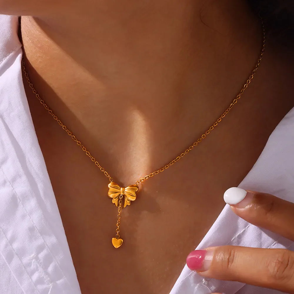 Gold bow and heart drop necklace with delicate chain.