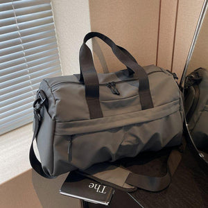 Gray nylon travel duffel bag with multiple zippered pockets and adjustable shoulder strap.