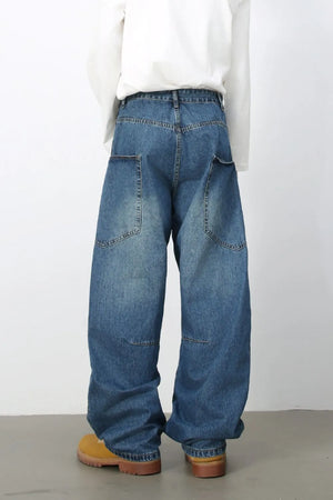 Medium wash denim balloon trousers with large front pockets and a relaxed fit.