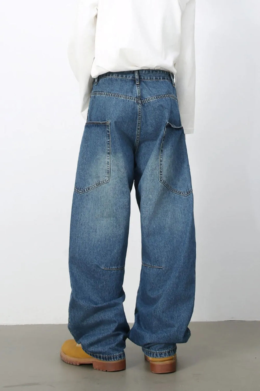 Medium wash denim balloon trousers with large front pockets and a relaxed fit.