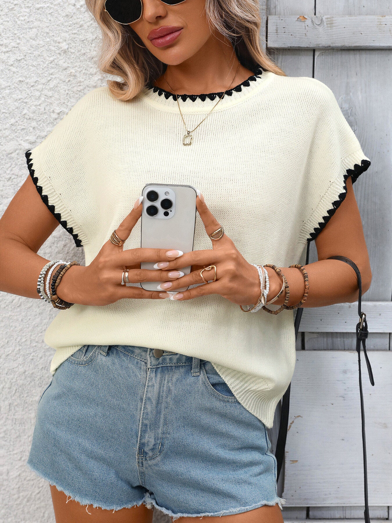 Off-white ribbed short-sleeve sweater with black contrast trim neckline and sleeves.