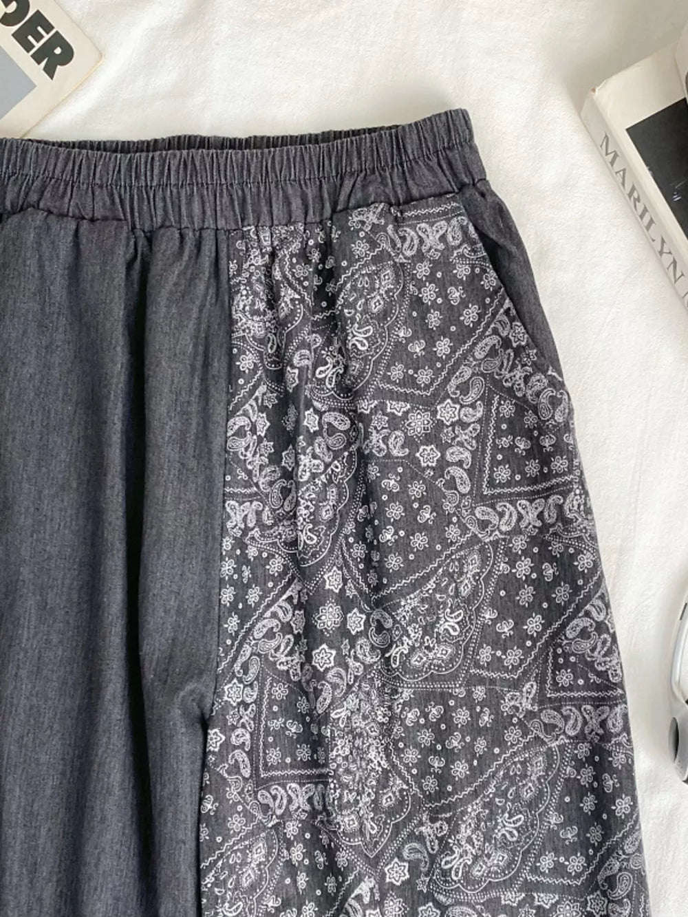 Black comfort jeans with elastic drawstring waist and bandana print panel.