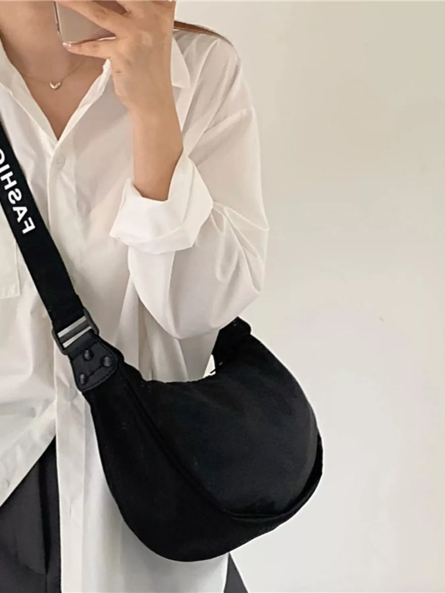 Black adjustable strap crossbody bag with white text detail on strap