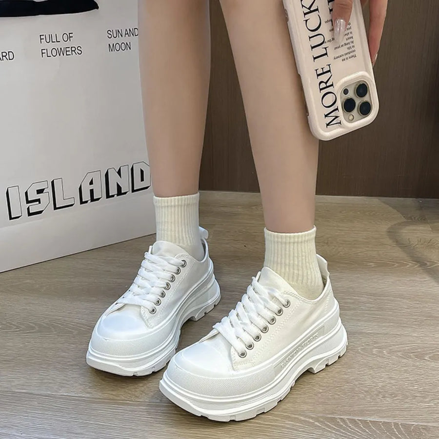 White canvas lace-up sneakers with chunky platform soles and ribbed socks.