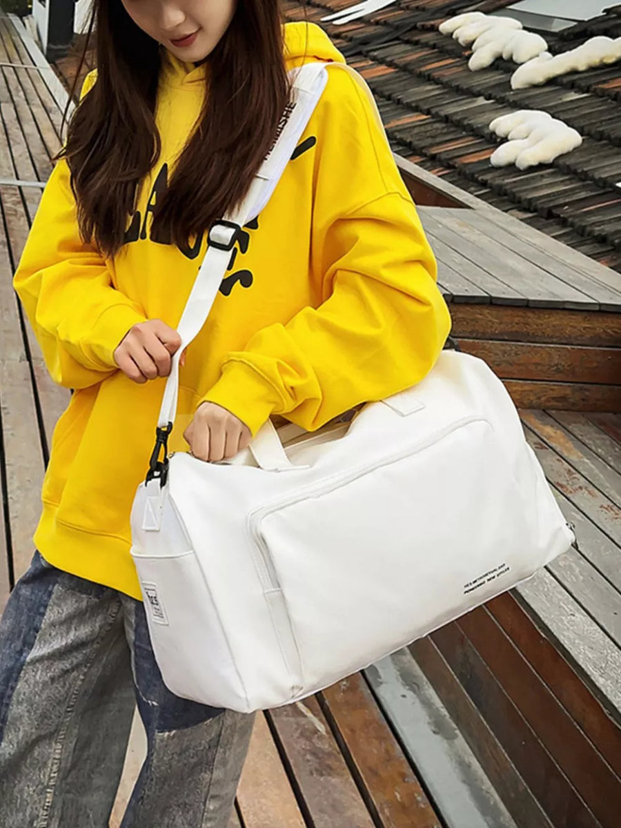 Spacious white canvas travel bag with detachable strap and exterior pockets, held by a woman.