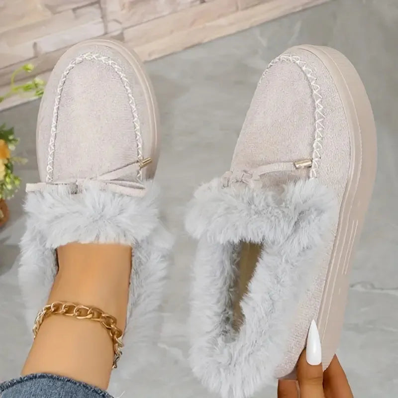 Beige suede loafers with shearling trim and bow detail.