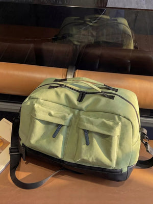 Green duffle bag with two front zip pockets and black trim.