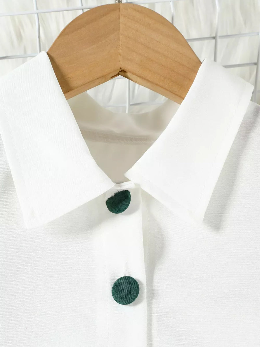 White baby top with green buttons and collar detail