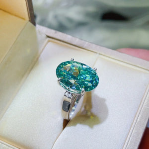 Emerald cut turquoise moissanite cocktail ring with diamond accents on band.