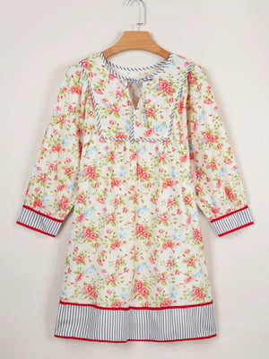 Floral cotton dress with puff sleeves, tie neck, and striped trim.