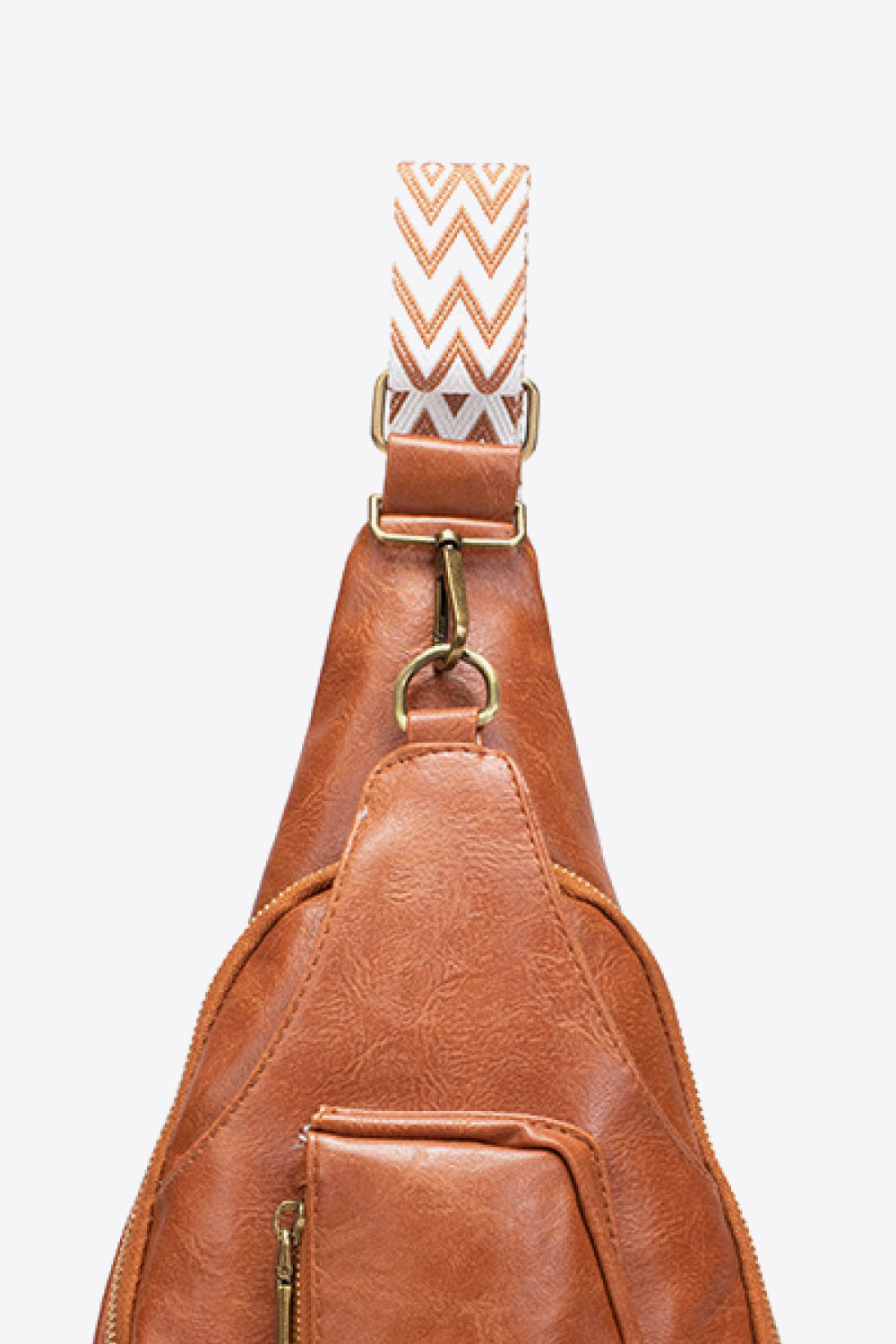 Brown textured sling bag with woven chevron strap detail and adjustable strap.