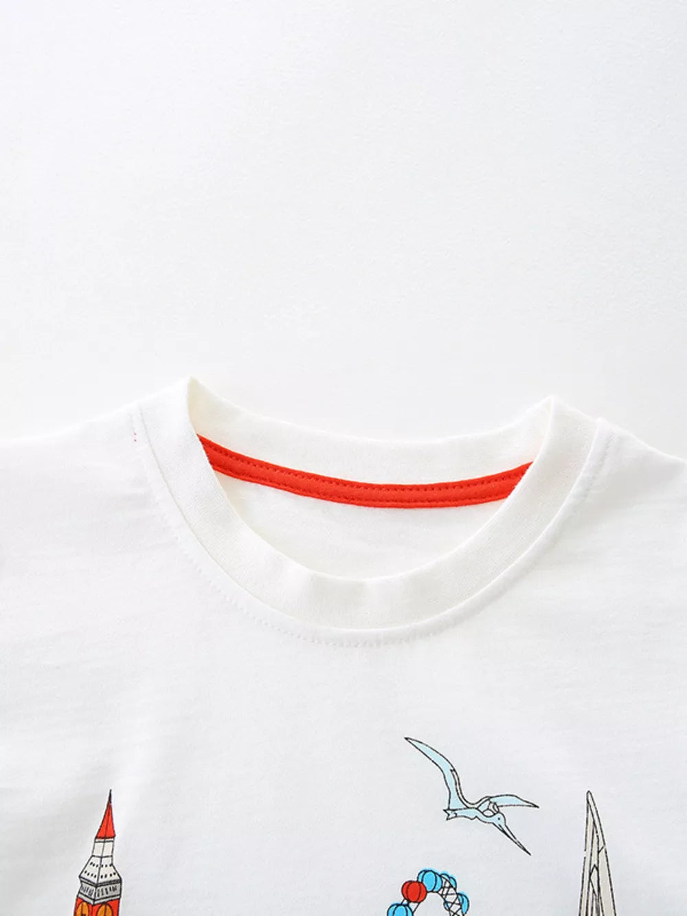 White cotton t-shirt with red trim, featuring a graphic print of London landmarks and flying creatures.