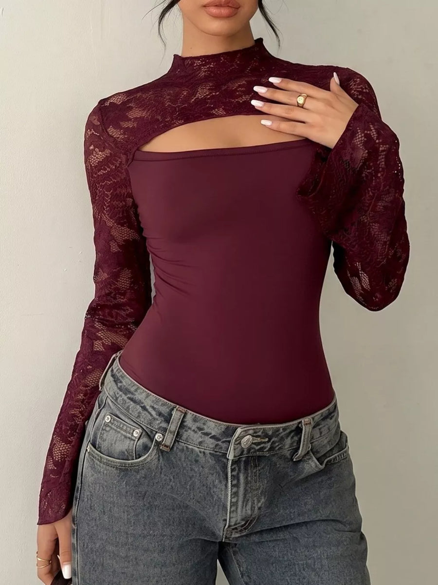 Burgundy lace shrug with cutout and mock neck, worn over a burgundy bodysuit and grey jeans.