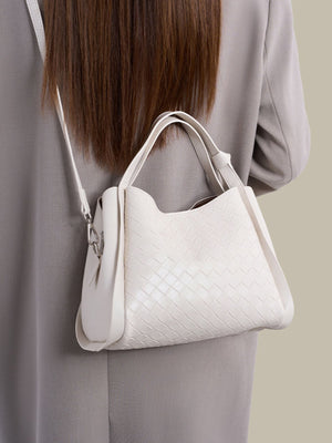 White crossbody bag featuring adjustable strap and woven