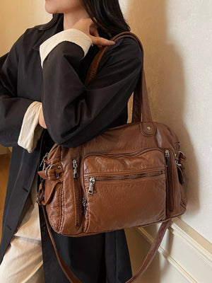 Brown faux leather crossbody bag with multiple zippered pockets and adjustable strap.